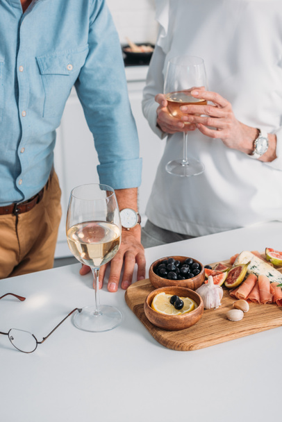 partial view of senior couple drinking wine and eating delicious snacks at home  - Fotoğraf, Görsel