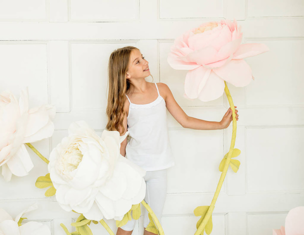 little girl posing in studio opposite decoration with artificial flowers - Foto, afbeelding