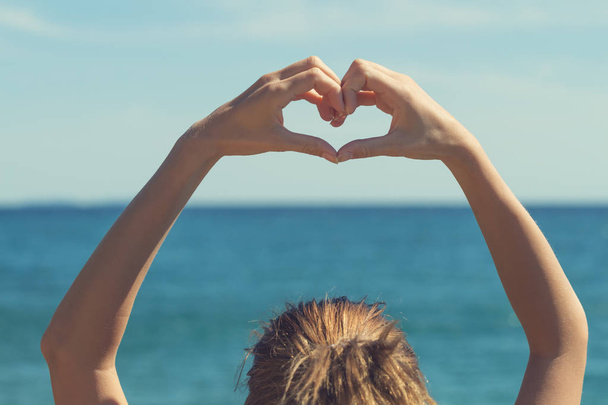 Dziewczyna co kształt serca z rąk na plaży - Zdjęcie, obraz