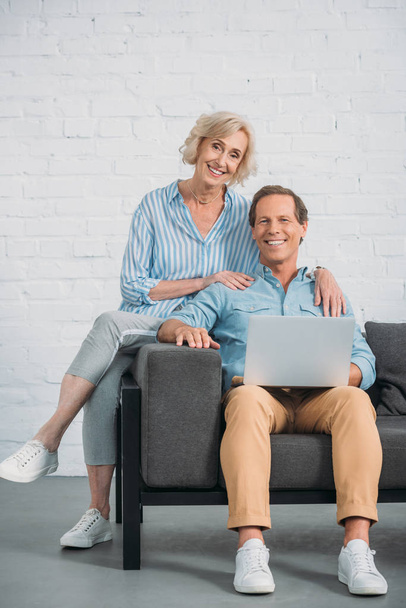 happy senior couple using laptop and smiling at camera - 写真・画像