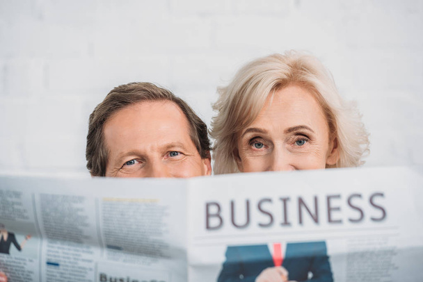 senior couple holding business newspaper and looking at camera - Fotó, kép