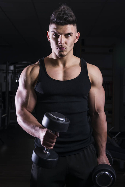 Muscular builder man training his body with dumbbell - Photo, Image