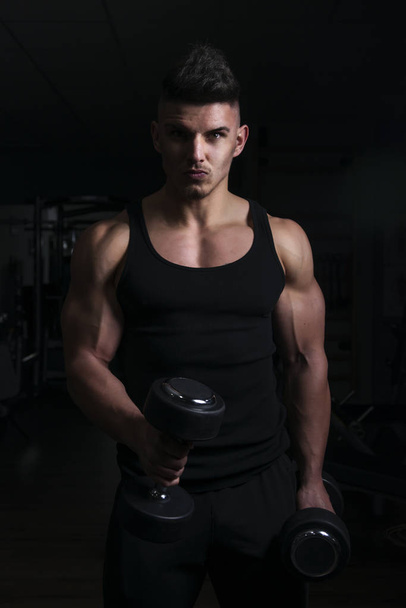 Muscular builder man training his body with dumbbell - Foto, Bild