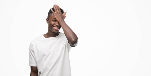 Jeune homme afro-américain portant un t-shirt blanc surpris avec la main sur la tête pour erreur, rappelez-vous erreur. Oublié, mauvais concept de mémoire
. - Photo, image