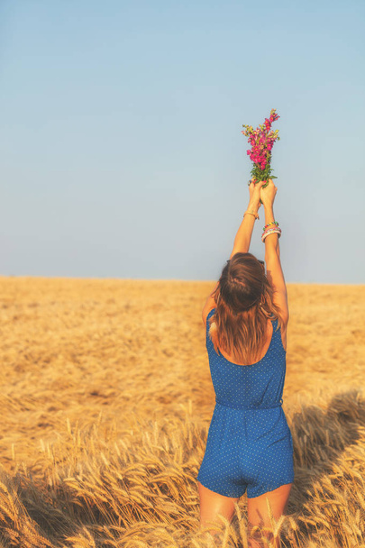женщина подняла руки с букетом полевых цветов на ячменном лугу
  - Фото, изображение