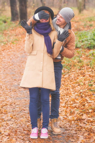 Glücklich lächelnder Mann bedeckt weibliche Augen mit Hand im Herbstpark  - Foto, Bild