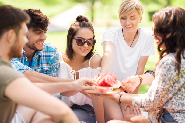 happy friends eating watermelon at summer picnic - Фото, изображение