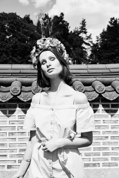 black and white photo of gorgeous young woman in elegant headdress posing outdoors  - Фото, зображення