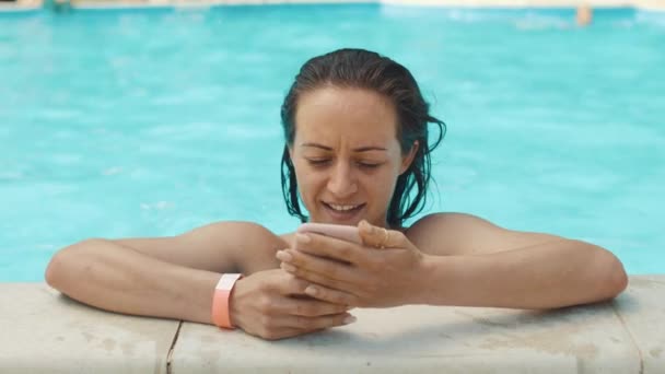 Young woman uses a smartphone in a pool. - Filmmaterial, Video