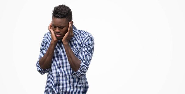 Молодой африканский американец в синей рубашке закрывает уши пальцами с раздраженным выражением для шума громкой музыки. Глухая концепция
. - Фото, изображение
