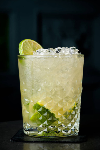 cold cocktail with lime and lemon. A glass of dew drops. Freshness, alcohol, bar. Black background - Photo, Image