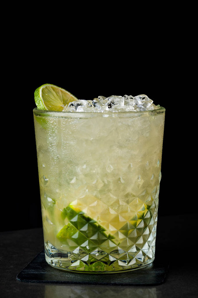 cold cocktail with lime and lemon. A glass of dew drops. Freshness, alcohol, bar. Black background - Фото, зображення