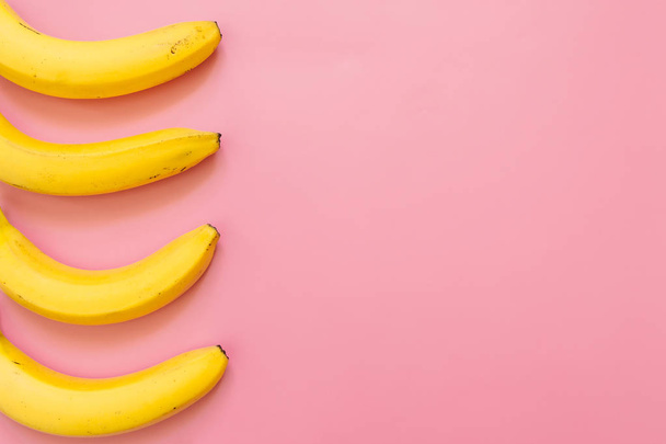 Four bananas border frame on pink background. Empty space for text. Minimalist concept. - Photo, Image