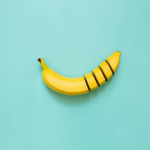 Cut banana, slices, dices arranged on square cyan green, blue, ultramarine background. Room for text. Minimalist concept. - Foto, imagen