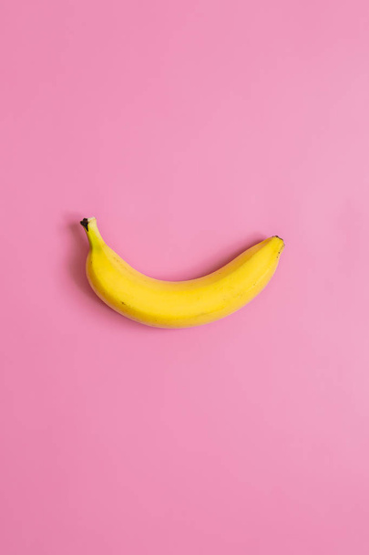 One, single banana on pink vertical background. Room for text. Minimalist concept. - Valokuva, kuva