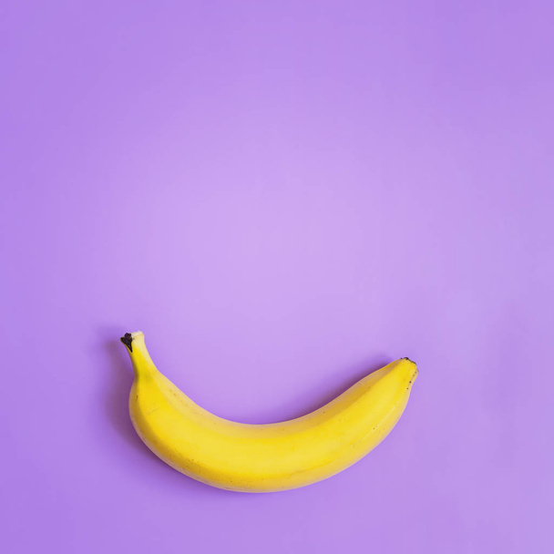 Uno, plátano simple sobre fondo cuadrado violeta de neón púrpura. Espacio para texto. Concepto minimalista
. - Foto, Imagen