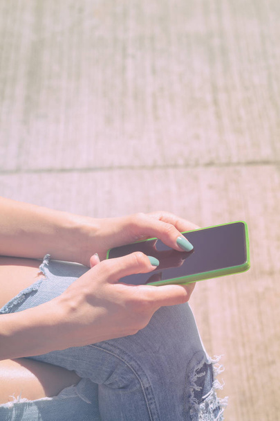 donna utilizzando smartphone mentre seduto su sfondo di legno
  - Foto, immagini