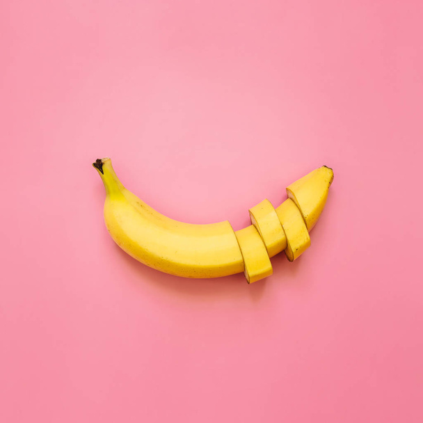 Řez, banán, plátky, kostičky, které jsou uspořádány na pastelově růžové čtverce pozadí. Místo pro text. Minimalistický koncept. - Fotografie, Obrázek