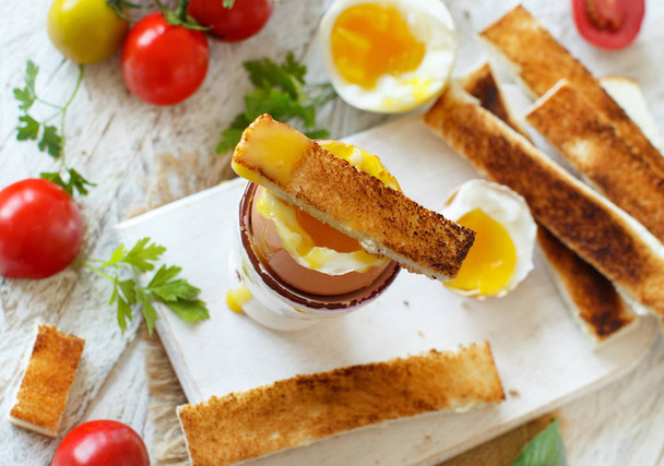  Naměkko vařená vejce s toasty a rajčaty na bílý dřevěný stůl horní pohled - Fotografie, Obrázek