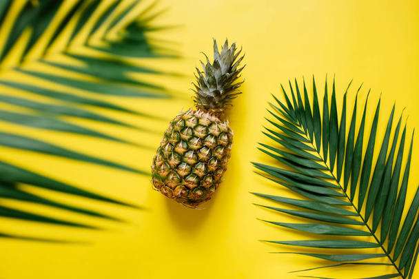 Ripe pineapple on vibrant yellow background isolated. Palm leaves border frame. Minimalist style trendy tropical concept. Room for text, copy, lettering. - Foto, Bild