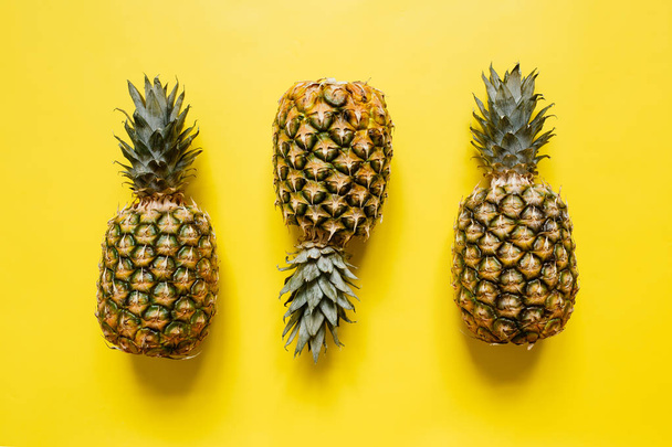 Tree ripe pineapples on vivid yellow background isolated. Minimalist style trendy tropical concept. - Fotoğraf, Görsel