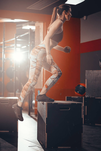 Молода підтягнута жінка стрибає на коробках у спортзалі
 - Фото, зображення