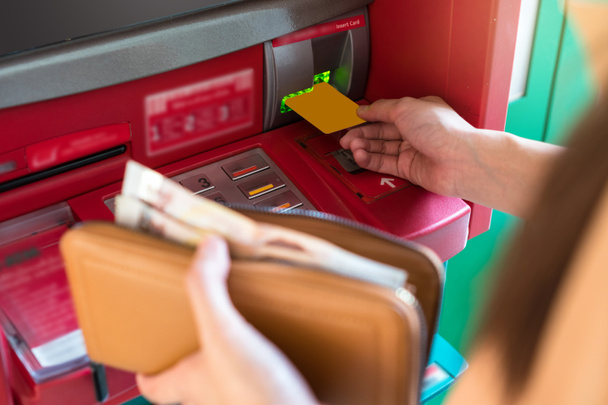 Женщина крупным планом держит кошелек и снимает наличные через банкомат, бизнес Автоматический кассир концепции
 - Фото, изображение