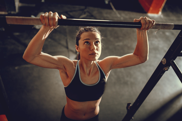 Młoda kobieta mięśni robi pull-up ćwiczenia w siłowni - Zdjęcie, obraz