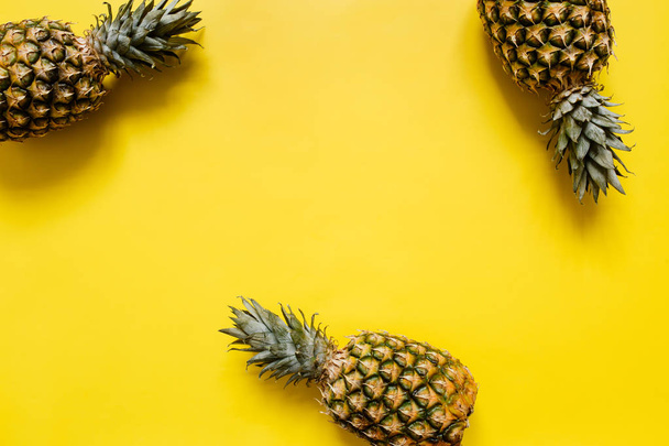 Ripe pineapples border frame on vivid yellow background isolated. Minimalist style trendy tropical concept. Empty space for text, copy, lettering. - Foto, imagen