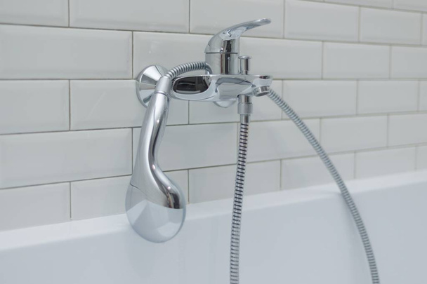 Close-up of chrome shower, faucet, in the bathroom covered decorative ceramic tiles with white glossy bricks - Фото, зображення