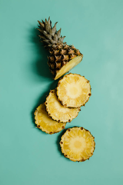 シアン ブルー、ターコイズ ブルーの無地の背景に熟したパイナップルをスライス. - 写真・画像