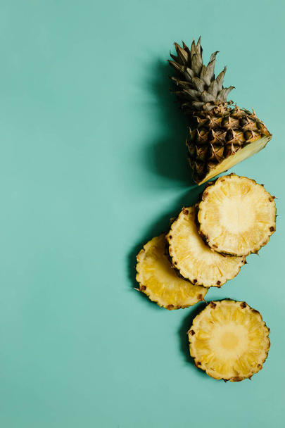 Sliced ripe pineapple on cyan blue, turquoise plain background. Room for text, copy, lettering. - 写真・画像