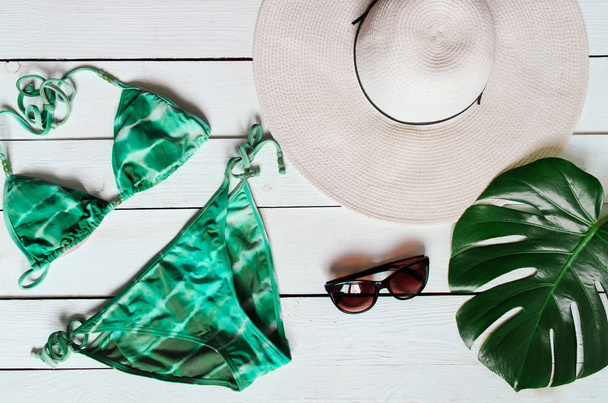 Bikinipuku, hattu, aurinkolasit, meritähti, vihreä plam leaf järjestetty puinen baclground. Kesälomien käsite. Trooppinen juliste lippu, postikortti
. - Valokuva, kuva