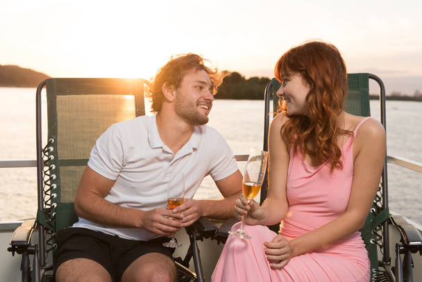 Пара закоханих дивиться один на одного, зустрічаючи захід сонця на яхті
 - Фото, зображення