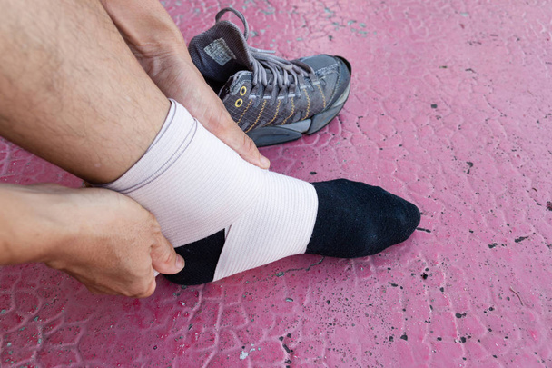 Atleta masculino aplicando tejido elástico Tejido elástico envuelto alrededor de las piernas de un jugador de fútbol, Lesiones deportivas
. - Foto, imagen