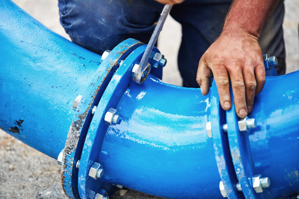 Manos trabajadoras atornillando tuercas en nuevas tuberías de agua de bebida - de cerca
 - Foto, Imagen
