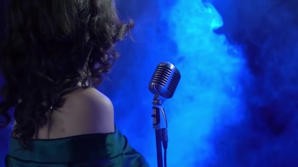 Güzel bir kız sahnede duruyor ve bir mikrofon mavi ligts ve duman içinde şarkı söylüyor - Video, Çekim