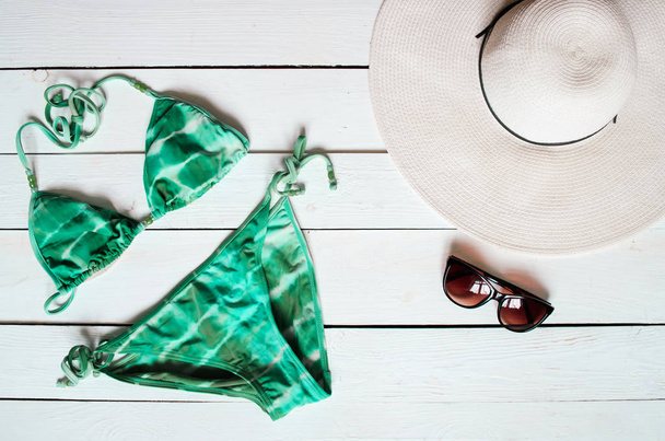 Combinaison de bikini verte, chapeau, lunettes de soleil, étoile de mer disposée sur un sol en bois. Vacances d'été concept de vacances. Bannière affiche tropicale, carte postale
. - Photo, image
