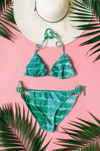 Пляжная одежда и тропические листья расположены на розовом фоне. Летние каникулы минималистский стиль
. - Фото, изображение
