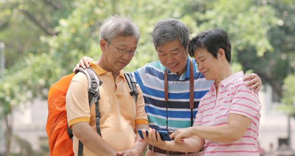 Senior old friends go travel together with backpack, cellphone and camera - Photo, Image