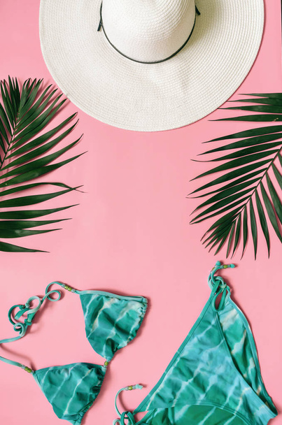 Beach kleding en tropische bladeren gerangschikt op roze achtergrond. Zomer vakantie minimalistische stijl concept. - Foto, afbeelding