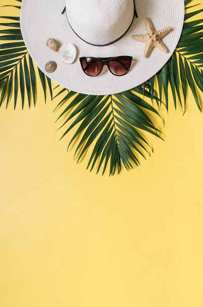 Chapeau de paille, lunettes de soleil et feuilles de palmier tropical disposées sur fond jaune uni. Concept de vacances tropicales. Espace vide pour copier, texte
. - Photo, image