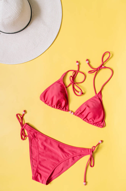 Biquíni aquamarine maiô e chapéu de palha dispostos sobre fundo rosa claro. Conceito criativo estilo minimalista
. - Foto, Imagem