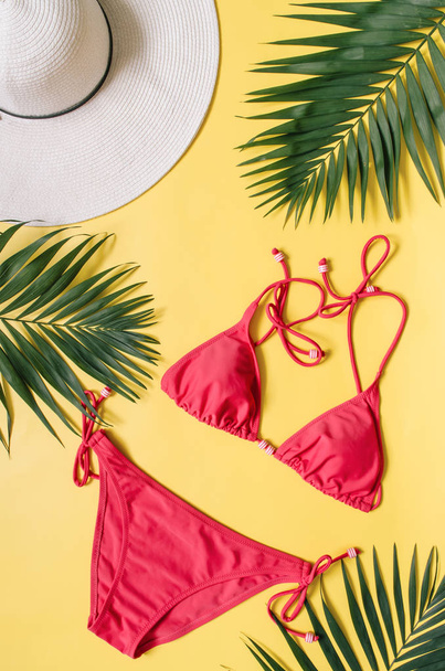 Vêtements de plage et feuilles tropicales disposées sur fond jaune. Vacances d'été concept de style minimaliste
. - Photo, image