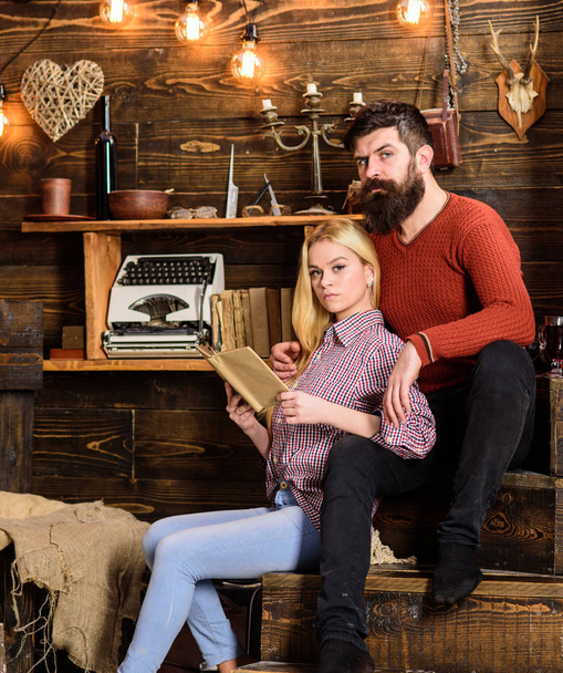Couple in love reading poetry in warm atmosphere. Romantic evening concept. Couple in wooden vintage interior enjoy poetry. Lady and man with beard on dreamy faces with book, reading romantic poetry - Foto, Bild