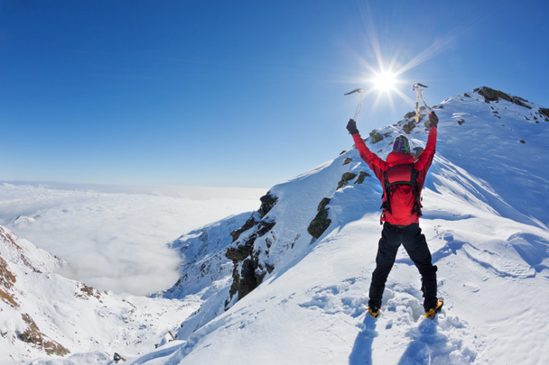 Bergsteiger erreicht die Spitze eines schneebedeckten Berges in einer sonnigen - Foto, Bild