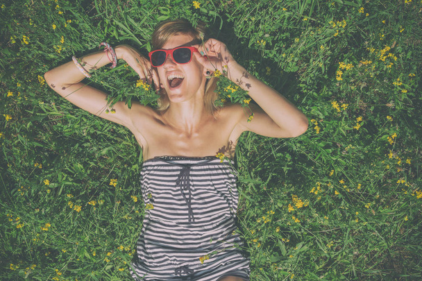 счастливая улыбающаяся женщина в солнцезащитных очках, лежащая в луже с желтыми цветами
  - Фото, изображение