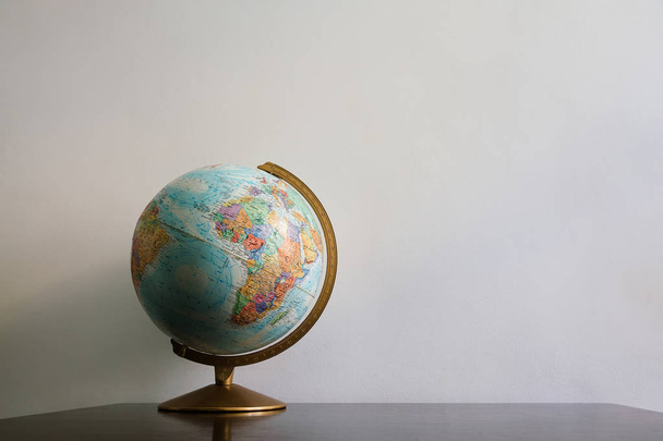 Globus-Modell auf dunklem Holztisch. weiße Wand leeren Raum Hintergrund. - Foto, Bild