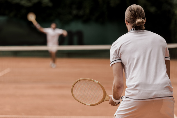 вид теннисистов в ретро-стиле во время игры на теннисном корте
 - Фото, изображение