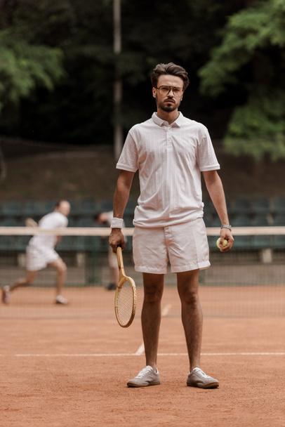 тенісист в стилі ретро стоїть з ракеткою і м'ячем на корті
 - Фото, зображення